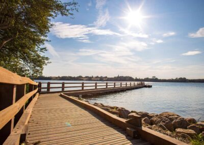 Center for verdensmål Træpromenade langs vandet i Sonderborg med solskin og blå himmel.