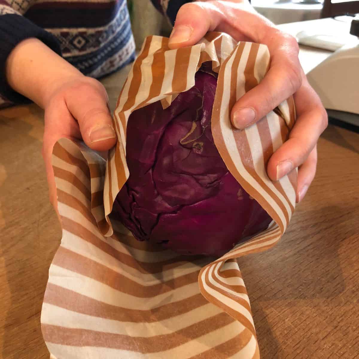 Person holder en bivoksklud pakket ind i papir, klar til brug.