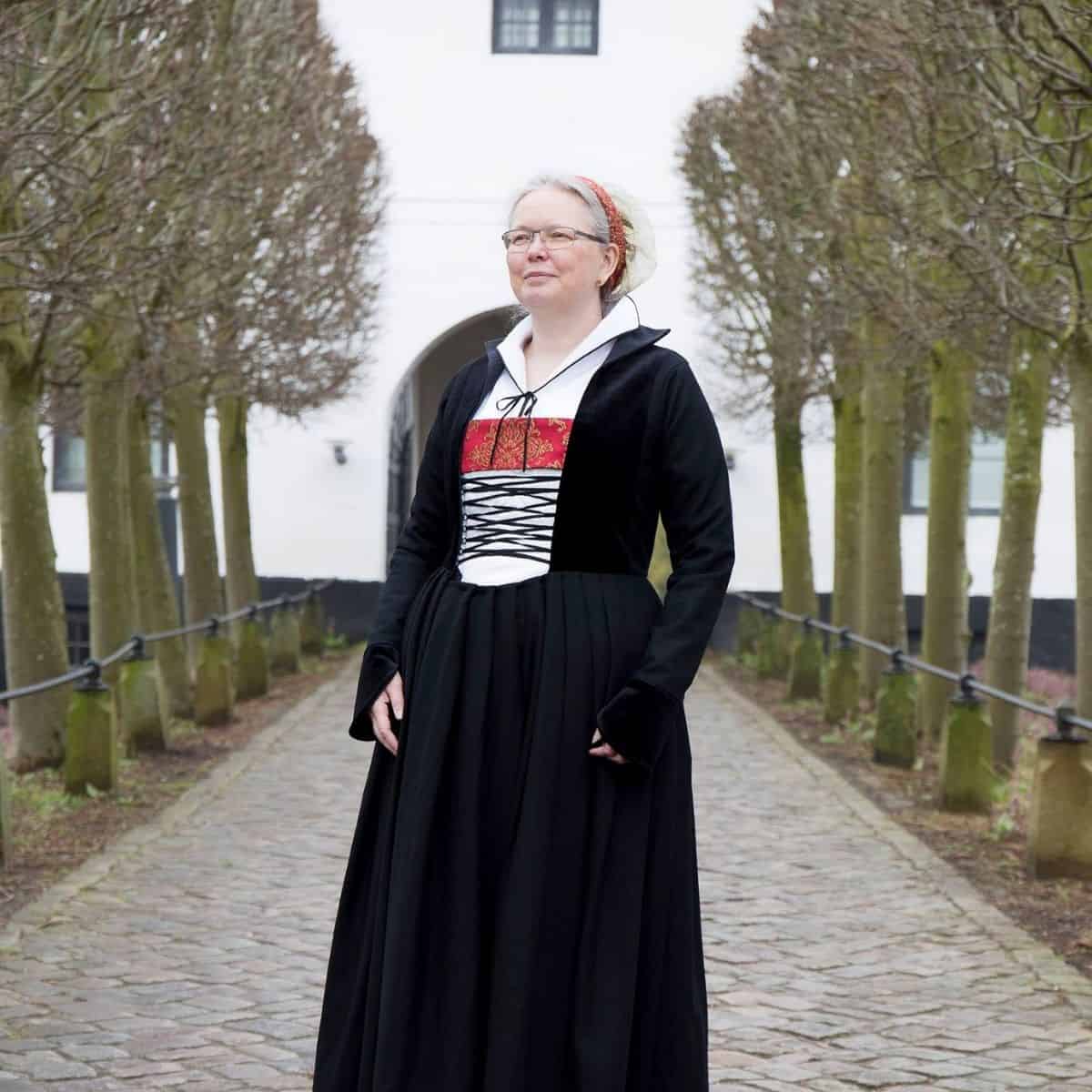 Kvinde i historisk dragt foran slot i Sonderborg, Danmark.
