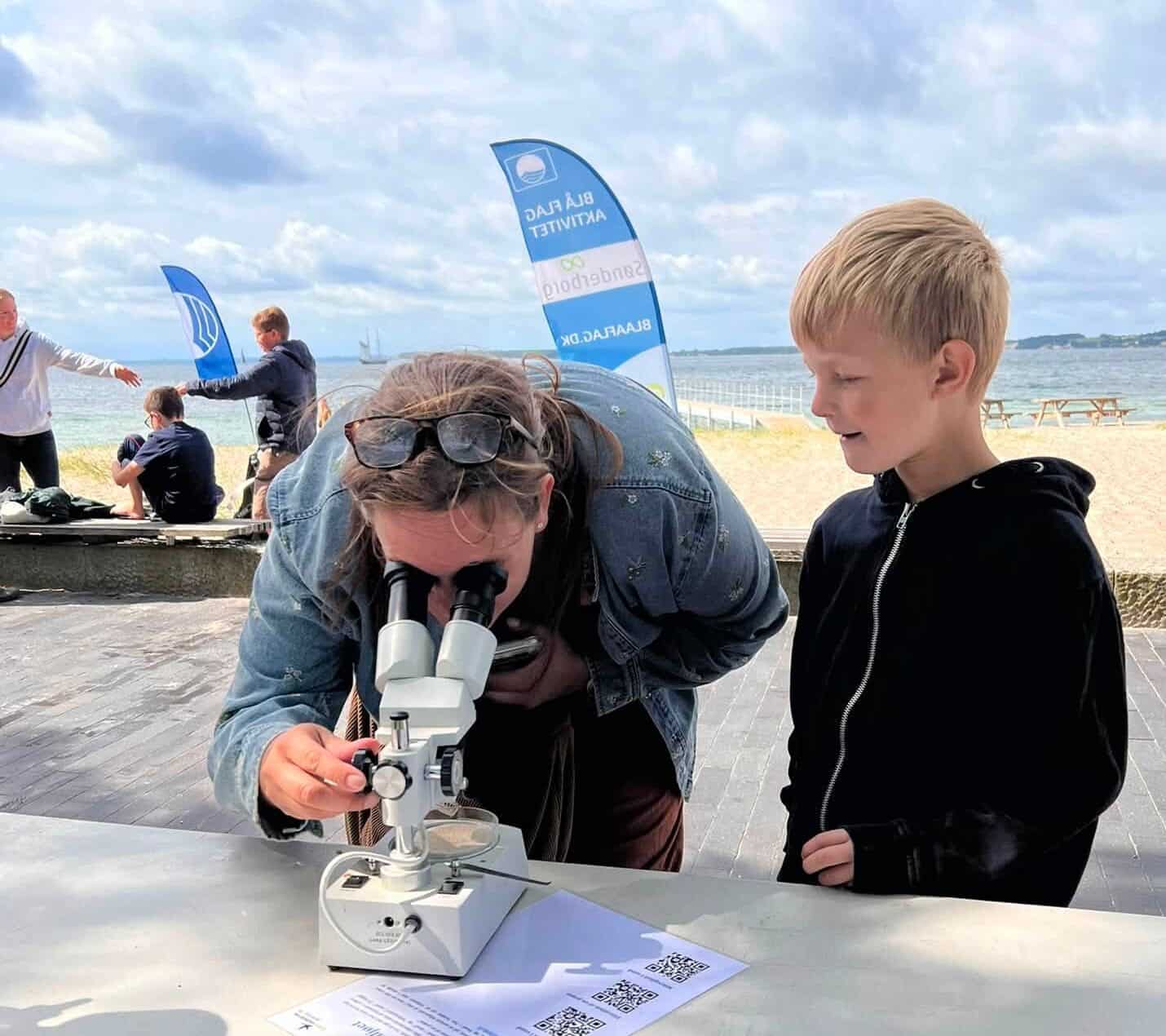 Børn undersøger med mikroskop ved stranden i Sonderborg.