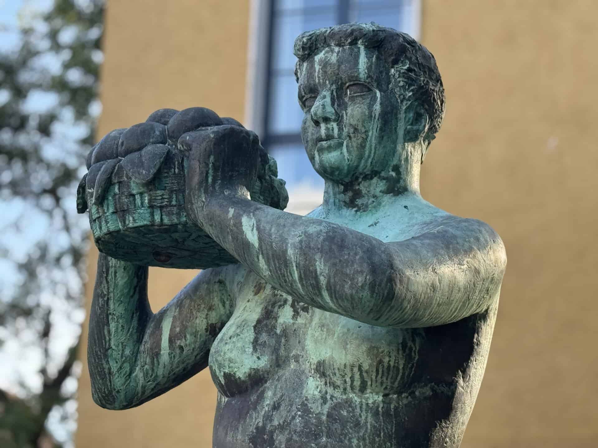 Alspigen 75 år Bronzeskulptur af barn, der bærer en kurv, i Sonderborg.