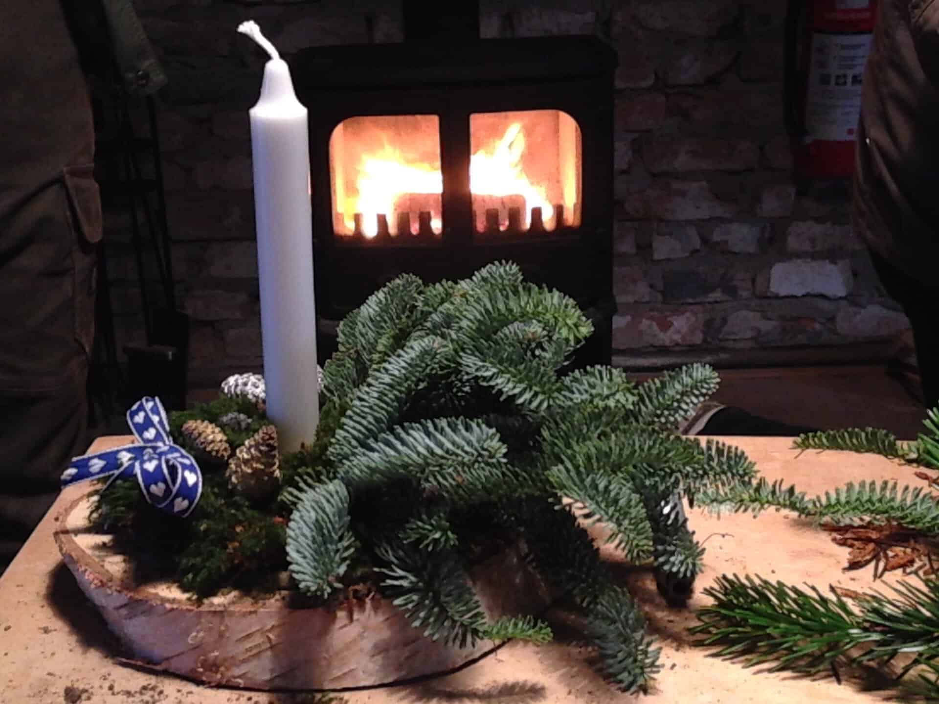 Lysende juledekoration med gran, lys og bål i Nørreskoven.