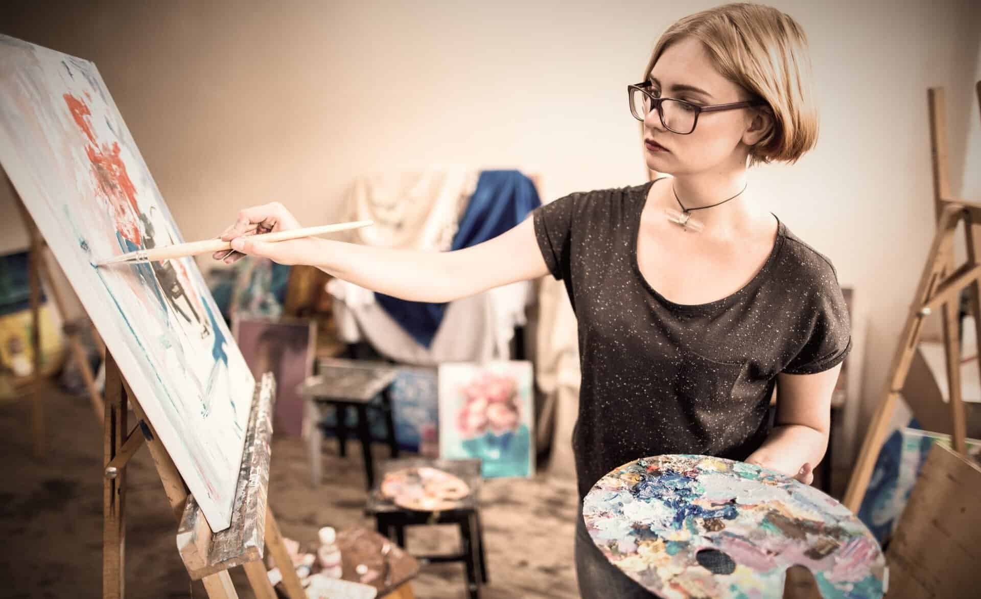 Kvinde maler på lærred under begynderkursus i kunst på Sønderjyllands Kunstskole.