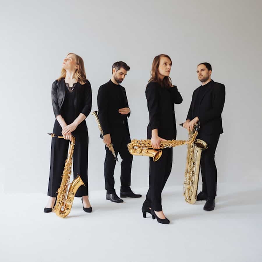 Saxofonkvartet med fire musikere i sort tøj mod hvid baggrund.